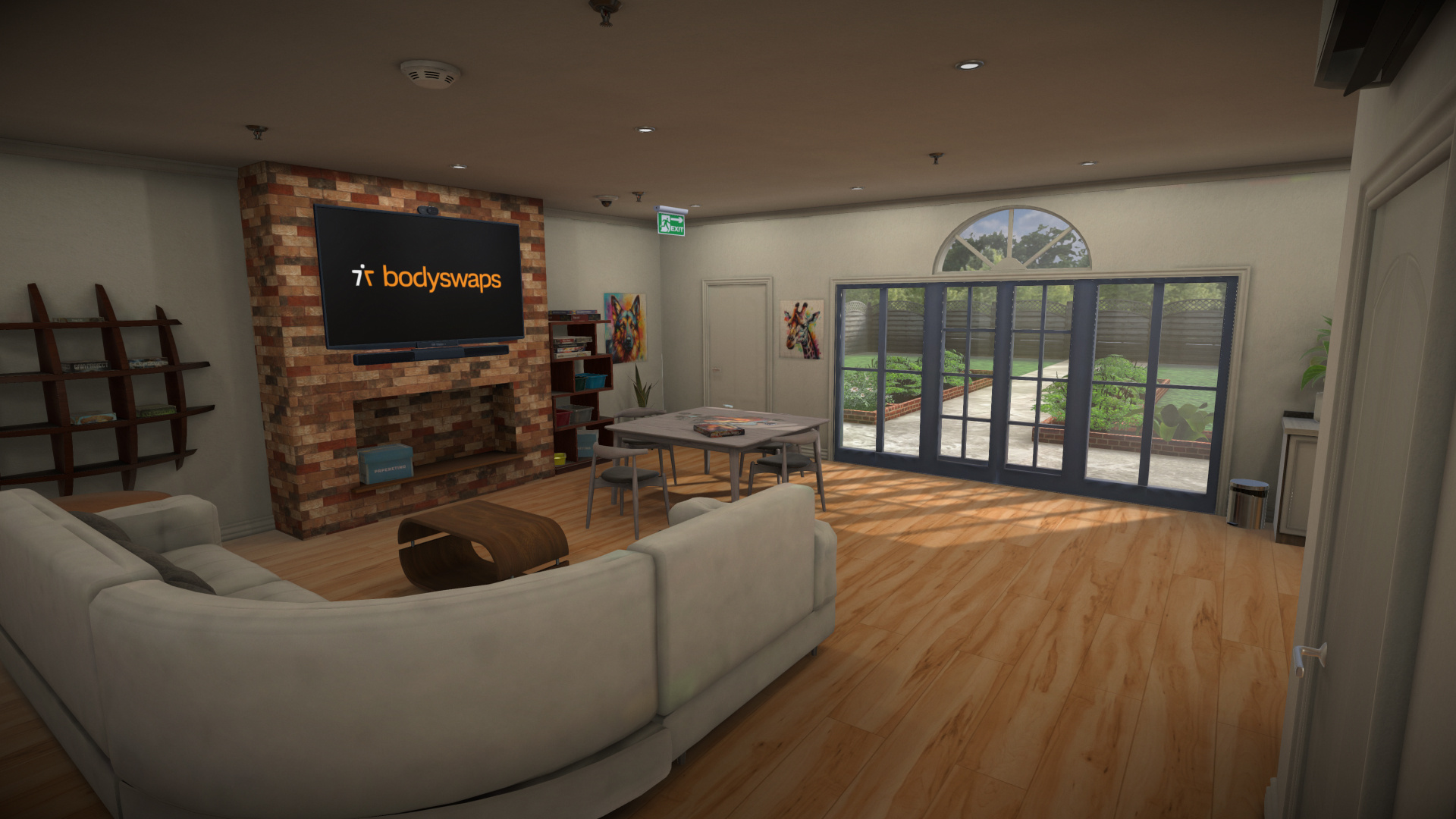 Open plan with wooden floors, a floor to ceiling brick fire place with a tv, a big, grey modular couch and a working desk next to glass doors
